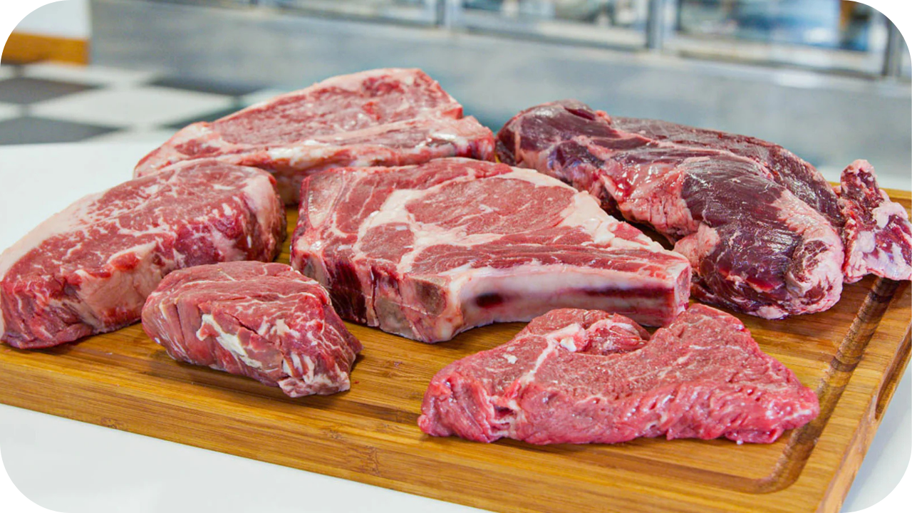 Selection of raw Wagyu steak cuts displayed on a wooden board, showcasing marbling and thickness for meal prep.