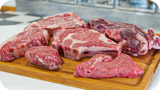 Selection of raw Wagyu steak cuts displayed on a wooden board, showcasing marbling and thickness for meal prep.