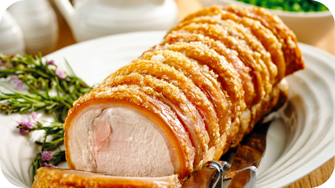 Crispy roast pork with golden crackling served on a white plate with herbs.