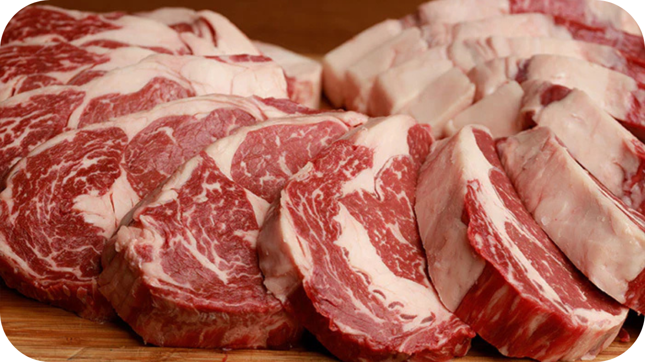 Freshly sliced Black Angus ribeye steaks arranged on a wooden board, showcasing rich marbling and thick cuts.