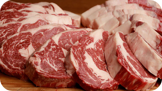 Freshly sliced Black Angus ribeye steaks arranged on a wooden board, showcasing rich marbling and thick cuts.