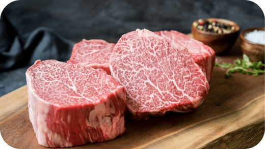 Fresh Wagyu beef fillet steaks with rich marbling on a wooden board.