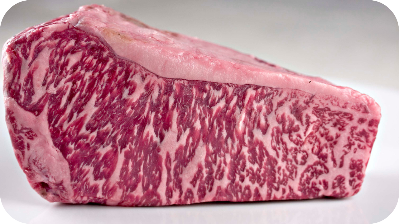 Two thick, raw sirloin cap steaks with a prominent fat cap and rich marbling, on a dark slate with thyme and peppercorns.