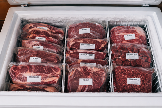 Cryovac sealed beef steaks and roasts labelled and stacked in a home chest freezer