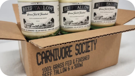 Open cardboard box showing Carnivore Society jars of grass-fed beef tallow labelled 500ml, packed neatly in rows.