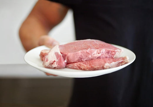 Person holding raw meat steaks representing protein-rich foods commonly used to build muscle on the carnivore diet