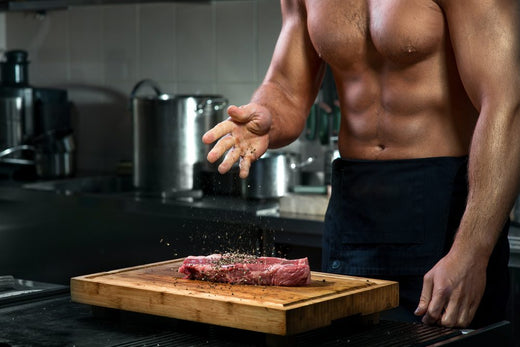 Athlete seasoning raw steak before cooking, showing high protein meal preparation in a carnivore diet for athletes