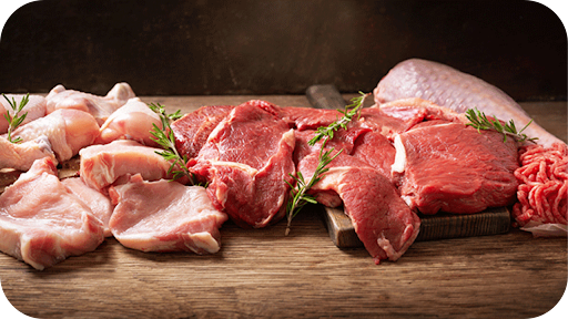 Variety of raw beef, chicken, pork, and turkey cuts with herbs on a wooden board, showing nutrient-dense meats for women’s health.