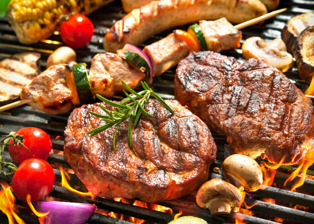 Grilled beef steaks, including rump cap, sizzling on a barbecue grill alongside skewered vegetables and mushrooms, ready for a BBQ feast