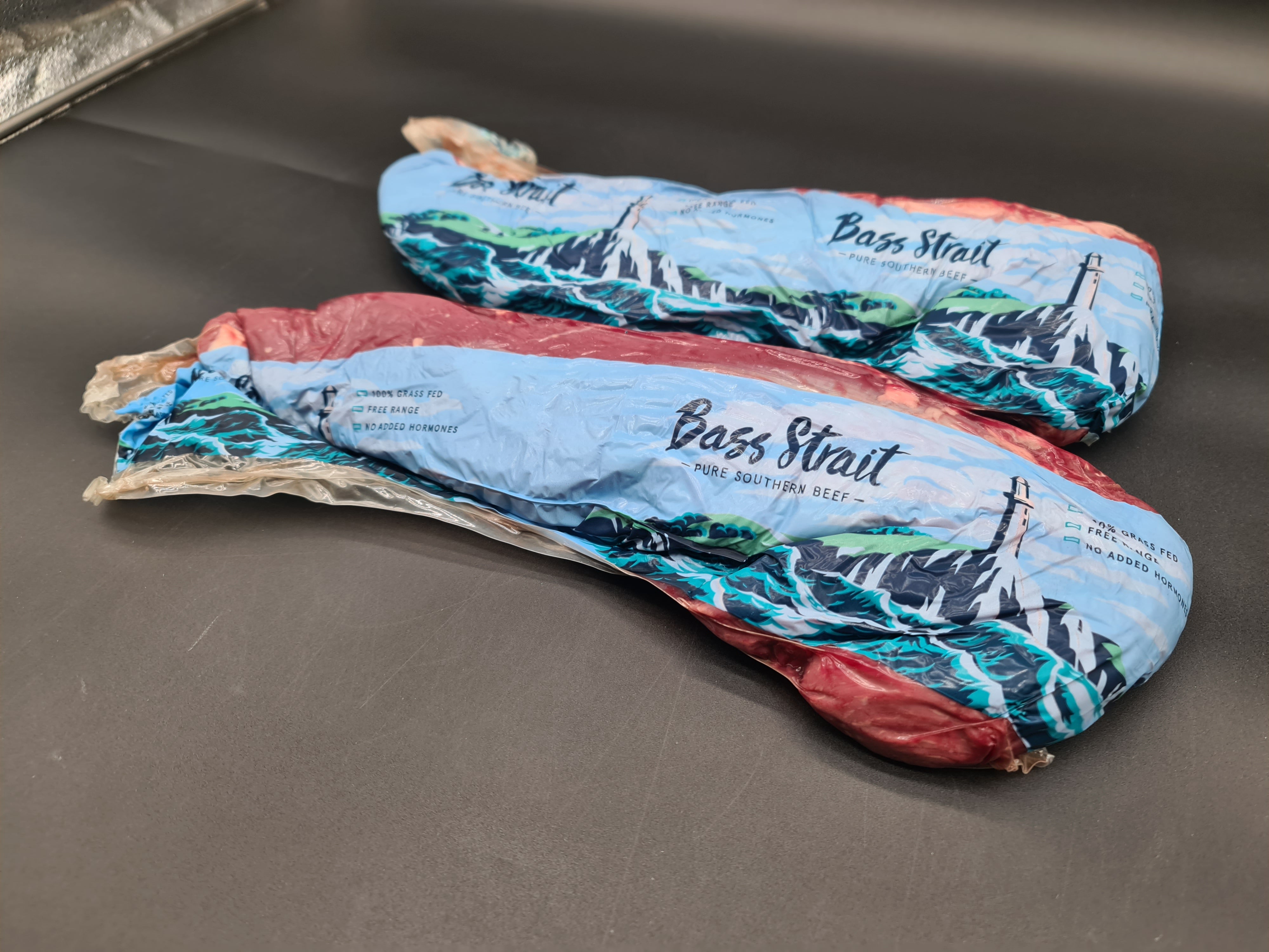 Two premium beef cuts side by side on a dark surface