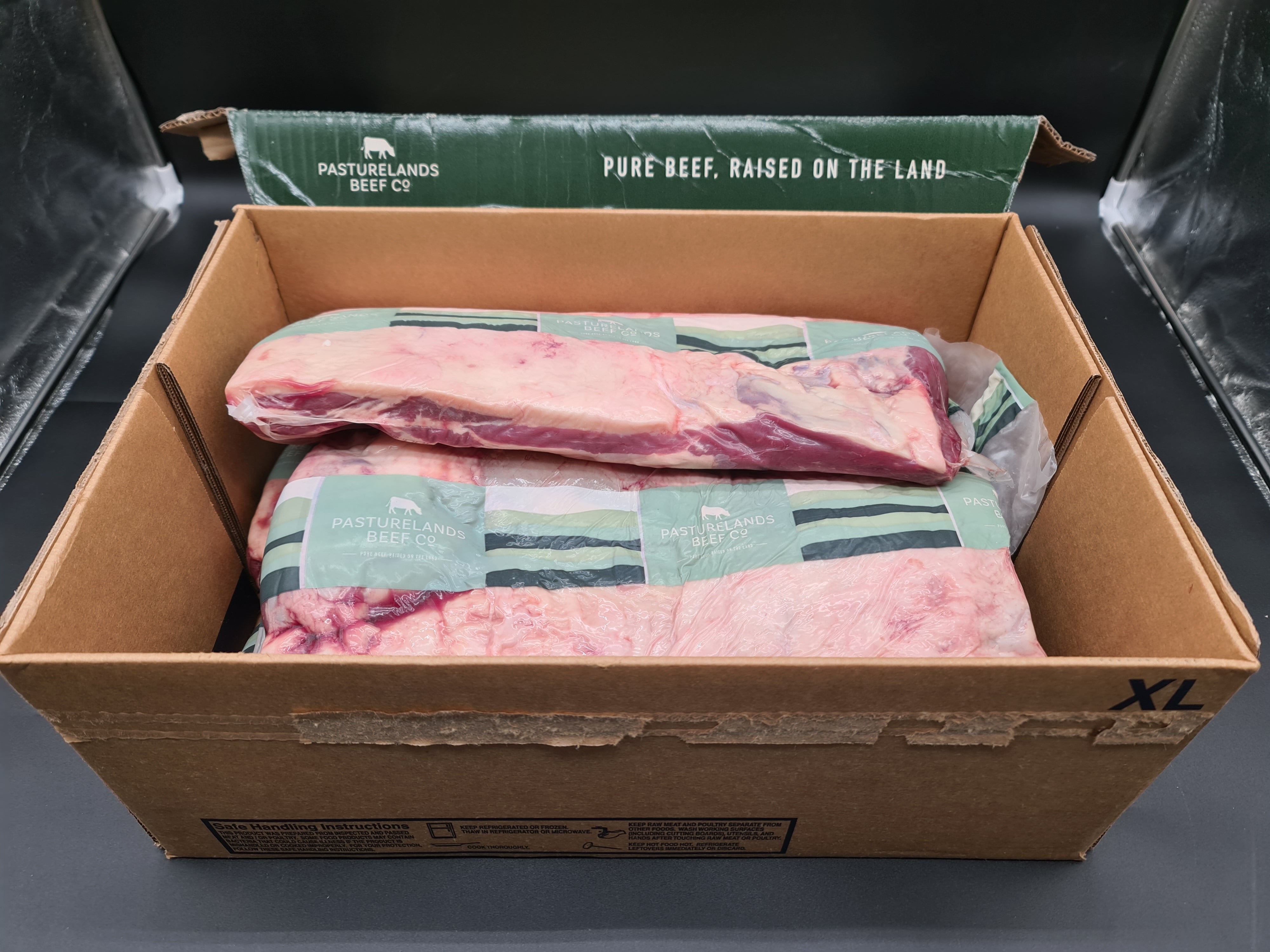 Open box filled with premium beef cuts in clear packaging