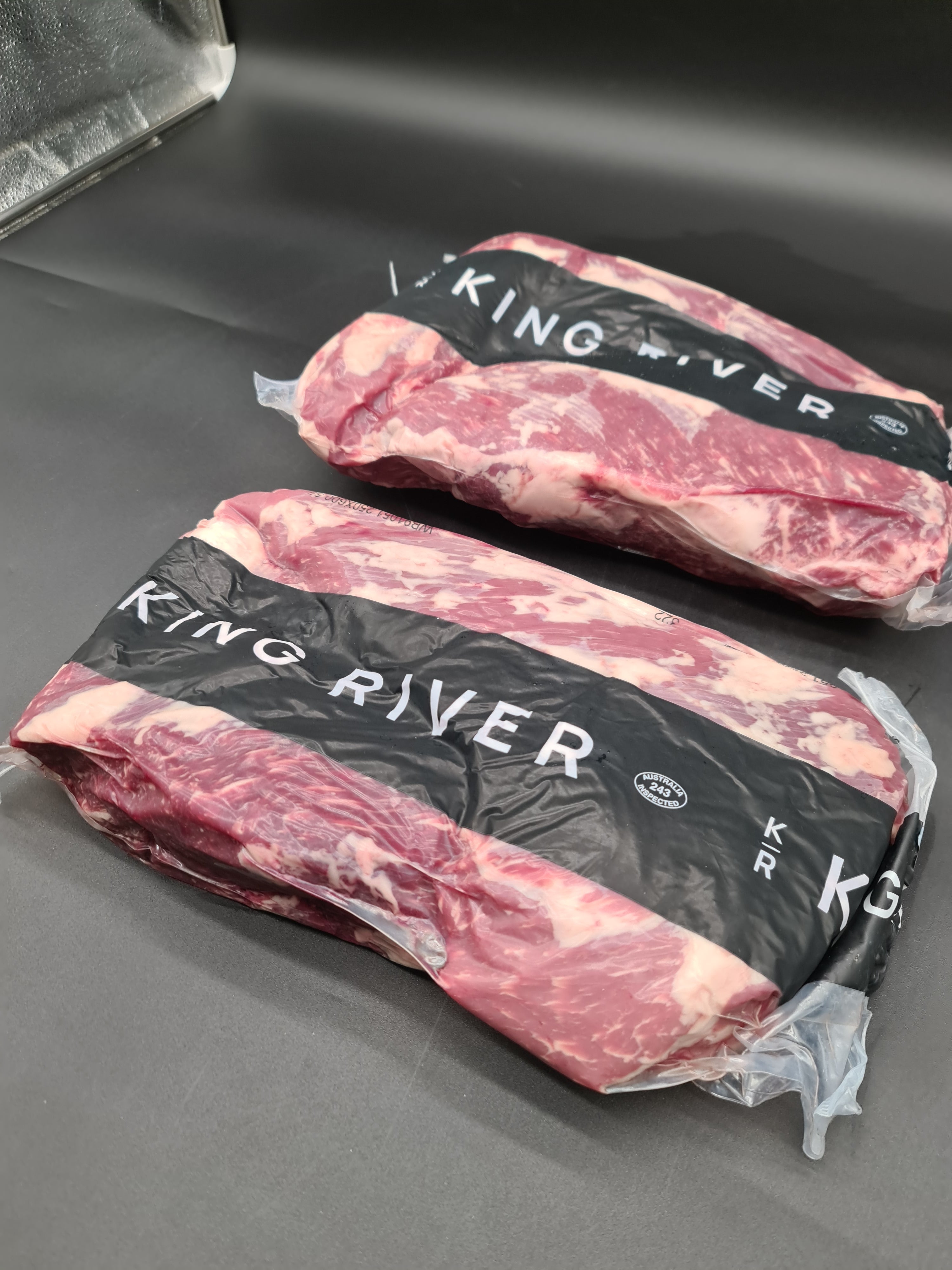 Open branded meat box with vacuum-packed cuts inside
